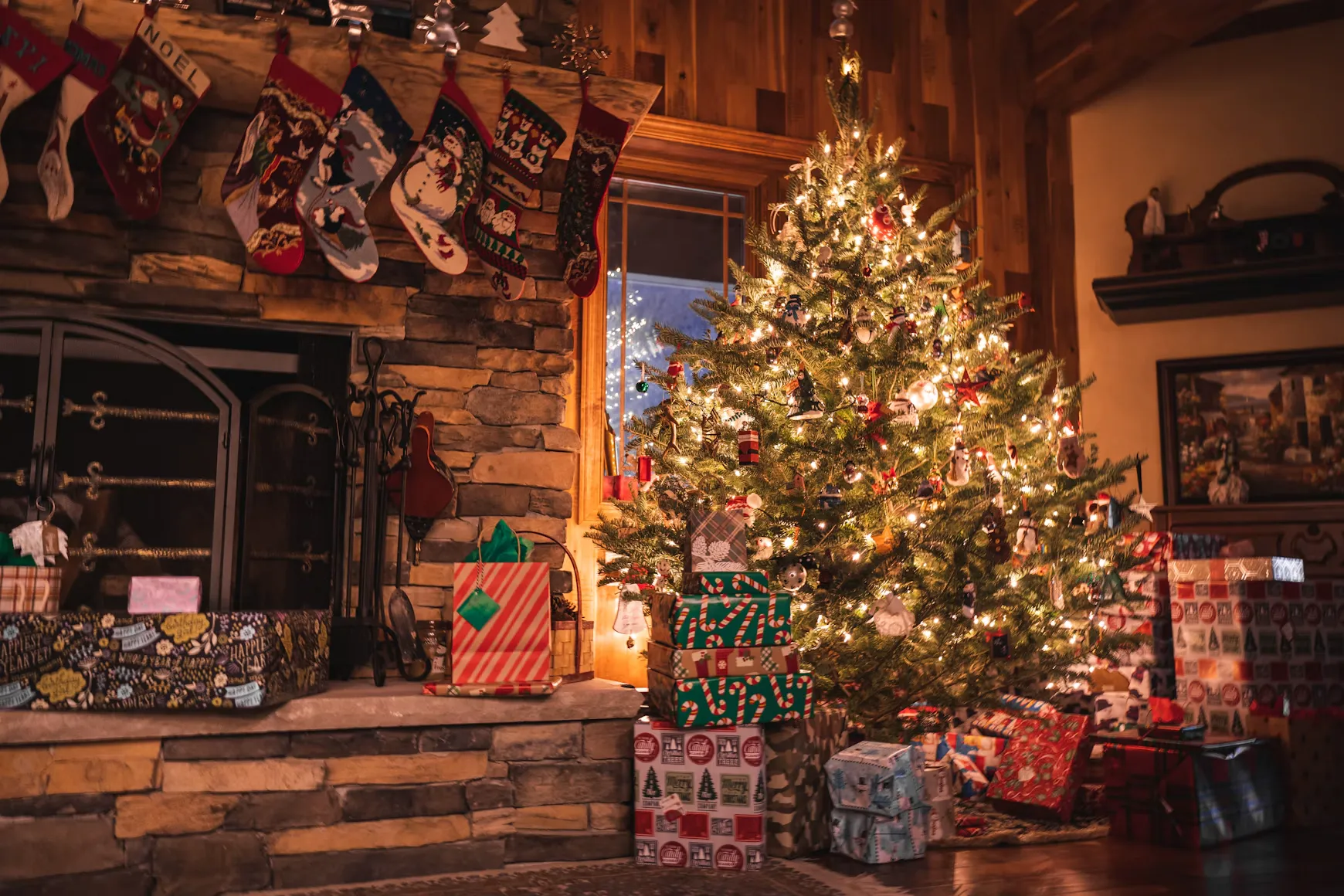 Sfeervolle kerstkamer met verlichte kerstboom, cadeaus en kerstsokken bij de open haard